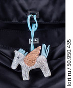 Close-up of an elegant bag charm featuring a Pegasus-shaped pendant encrusted entirely with sparkling rhinestones on black bag. Стоковое фото, фотограф Виталий Сова / Фотобанк Лори