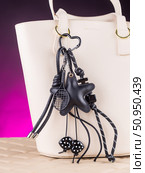 Close-up of a stylish leather bag accessory featuring a detailed leather charm. Accompanying the set are black keychains with sea star motifs and a decorative cord adorned with beads. Стоковое фото, фотограф Виталий Сова / Фотобанк Лори