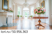 Bright Opulent Interior of a Grand Historic Estate with High Ceilings, Crystal Chandelier, and Sumptuous Floral Arrangements, Ideal for Event Celebration. Стоковое AI-изображение, AI-художник Данила Большаков / Фотобанк Лори