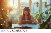 A studious young student enjoying a cozy home study session, deeply engrossed in a book with headphones on, bathed in warm golden hour light. Стоковое AI-изображение, AI-художник Данила Большаков / Фотобанк Лори