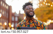 A confident African American man with a genuine smile and dapper eyeglasses, embodying urban success in a warmly illuminated environment. Стоковое AI-изображение, AI-художник Данила Большаков / Фотобанк Лори