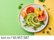 A deconstructed avocado salad artistically displayed on a dual-tone canvas. The pastel and deep shades provide a compelling contrast, highlighting the salad's vibrant colors and innovative presentation. Стоковое AI-изображение, AI-художник Nart / Фотобанк Лори