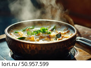 A steaming French onion soup with roasted poblanos tantalizes the senses. Served in a hammered pewter bowl, its rich aroma promises a comforting and flavorful dining experience. Стоковое AI-изображение, AI-художник Nart / Фотобанк Лори