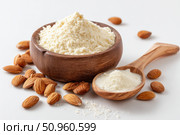 Almond flour. Almond nuts and almond flour in a wooden bowl and spoon. White table background. Grated almonds pile. Gluten-free produce for health. Low Carb Keto, celiac, paleo, and wheat-free diets. Стоковое AI-изображение, AI-художник Марина Демидюк / Фотобанк Лори