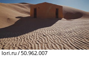 Weathered orange structure standing amid rippling desert sand, casting dramatic shadows against cloudless azure sky, emphasizing architectural decay within expansive arid terrain. Стоковое AI-видео, аниматор Данил Руденко / Фотобанк Лори