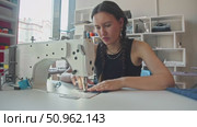 skilled tailor, is meticulously crafting denim garments in her workshop, using a sewing machine and adding embroidery. Стоковое видео, видеограф Strunov David / Фотобанк Лори