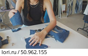 A young master in a specialized denim clothing store creates thick denim gloves. Стоковое видео, видеограф Strunov David / Фотобанк Лори