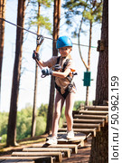 Girl Navigates a Rope Park Adventure Among Tall Trees During a Sunny Day Outdoors. Стоковое фото, фотограф Aleksandr Golubev / Фотобанк Лори