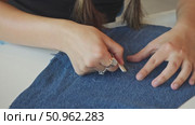 With a piece of chalk, the tailor draws a hand-shaped outline on the denim material. Стоковое видео, видеограф Strunov David / Фотобанк Лори