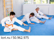 Focused guy in kimono stretching after group martial arts training. Стоковое фото, фотограф Яков Филимонов / Фотобанк Лори
