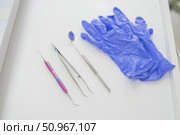 Dentist's table with sterile tools on a white background top view. A mirror, tweezers, a probe and gloves are on the doctor table. Oral hygiene, caries prevention, examination. Стоковое фото, фотограф Михаил Решетников / Фотобанк Лори