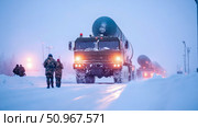 A convoy of large military transporter erector launchers carrying strategic missiles proceeds through a frozen, snow-blanketed expanse at twilight, embodying powerful defense capabilities for securit. Стоковое AI-изображение, AI-художник Данила Большаков / Фотобанк Лори