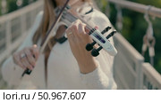 A beautiful girl in a white dress plays the violin standing on a footbridge. Стоковое видео, видеограф Tatiana Malinsky / Фотобанк Лори