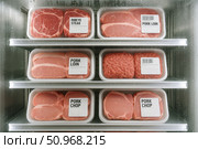 Various cuts of pork meat displayed in clear plastic packaging inside a refrigerator. Labels include pork loin, pork chop, and heavy style. Стоковое AI-изображение, AI-художник Nart / Фотобанк Лори