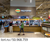 A woman walks into a store with a green shirt on. Russia. Moscow. 02.08.25. Редакционное фото, фотограф Ярославский Максим / Фотобанк Лори