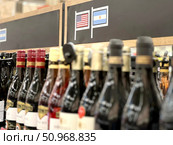 A row of wine bottles with a sign that says "USA" and "Argentina" on it. Russia. Moscow. 02.08.25. Редакционное фото, фотограф Ярославский Максим / Фотобанк Лори