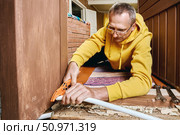Plumber trims plastic pipe using cutting tool to ensure proper connection surface for placing compression ring and mounting threaded fitting. Стоковое фото, фотограф Владимир Григорьев / Фотобанк Лори