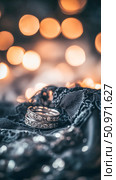 Silver rings on black lace fabric with warm bokeh lights in the background. Стоковое AI-изображение, AI-художник Евгения Пархоменко / Фотобанк Лори