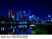 A city skyline is lit up at night with the lights reflecting on the water. Residential complex on Shelepikhinskaya embankment. Russia. Moscow. 03.08.2025. Редакционное фото, фотограф Ярославский Максим / Фотобанк Лори