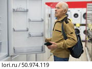 senor man pensioner buying fridge in showroom of electrical appliance store. Стоковое фото, фотограф Татьяна Яцевич / Фотобанк Лори
