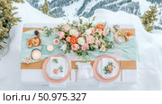 Romantic Mountaintop Dinner Setting: Elegant Table Decor with Floral Arrangements and Stunning Snowy Landscape. Стоковое AI-изображение, AI-художник Данила Большаков / Фотобанк Лори