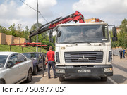 Процесс перемещения машины с одного участка дороги на другой с помощью эвакуатора завершен.  Машина снова  стоит на земле. Редакционное фото, фотограф Наталья Николаева / Фотобанк Лори