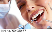 A female patient sits in a dentists chair as the dentist brushes her teeth during a routine dental cleaning. Стоковое AI-изображение, AI-художник Данила Большаков / Фотобанк Лори