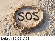 Large SOS message drawn in sand on beach surrounded by footprints, symbolizing distress, emergency, survival, or a call for help in a remote area. Стоковое AI-изображение, AI-художник Катерина Бондарец / Фотобанк Лори