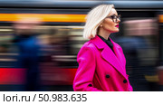 Fashionable woman in a bold fuchsia coat and chic eyeglasses looks forward amidst the blurred speed of a passing train. Стоковое AI-изображение, AI-художник Данила Большаков / Фотобанк Лори