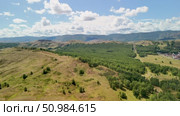 Bannoe Center, Russian Federation - July 27, 2025: Expansive golden grassland landscape under a bright blue sky with fluffy clouds and distant mountains, showcasing the beauty of nature and tranquility. Редакционное видео, видеограф Ирина Ручушкина / Фотобанк Лори