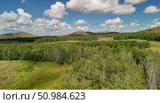 Bannoe Center, Russian Federation - July 27, 2025: Expansive golden grassland landscape under a bright blue sky with fluffy clouds and distant mountains, showcasing the beauty of nature and tranquility. Редакционное видео, видеограф Ирина Ручушкина / Фотобанк Лори