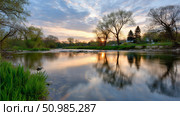 Beautiful sunset reflecting on a calm river in a serene natural setting. Стоковое AI-изображение, AI-художник Katsiaryna Repich / Фотобанк Лори