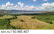 Bannoe Center, Russian Federation - July 27, 2025: Expansive aerial view of lush green forest and rolling hills under bright blue sky showcasing natural beauty and tranquility. Редакционное видео, видеограф Ирина Ручушкина / Фотобанк Лори