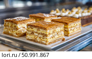 Mille feuille pastries sitting on white rectangular plate in bakery display case. Стоковое фото, фотограф Юрий Поздников / Фотобанк Лори