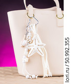 Close-up of a stylish leather bag accessory featuring a detailed leather charm. Accompanying the set are white keychains with sea star motifs and a decorative cord adorned with beads. Стоковое фото, фотограф Виталий Сова / Фотобанк Лори