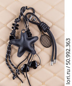 Close-up of a stylish leather bag accessory featuring a detailed leather charm. Accompanying the set are black keychains with sea star motifs and a decorative cord adorned with beads. Стоковое фото, фотограф Виталий Сова / Фотобанк Лори