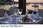 Wine glasses and seafood platter sitting on intimate table, sunset harbor view highlighting elegant seaside dining experience for couples. Стоковое AI-видео, аниматор Данил Руденко / Фотобанк Лори