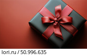 Black Gift Box With Red Ribbon on Red Background Ready for Celebration or Special Occasion. Стоковое AI-изображение, AI-художник Юлия Гапеенко / Фотобанк Лори