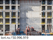 Building facade under construction with scaffolding and raw concrete walls. Стоковое фото, фотограф Данила Большаков / Фотобанк Лори