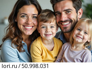 Mom and dad smile warmly, embracing their two young children. The family gathers in a cozy living room, filled with happiness and sunlight, enjoying quality time together Generative AI. Стоковое AI-изображение, AI-художник Юлия Петровская / Фотобанк Лори