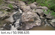 Aerial perspective showcases a beautiful waterfall flowing over rocks, surrounded by vibrant greenery, creating a peaceful and natural atmosphere in the landscape. Стоковое видео, видеограф Ирина Ручушкина / Фотобанк Лори