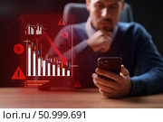 Investor analyzing market trends using a smartphone during a financial downturn in a professional setting. Стоковое фото, фотограф Сергей Толмачёв / Фотобанк Лори