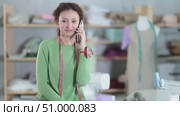 Female tailor talking on phone in sewing workshop. Стоковое видео, видеограф Яков Филимонов / Фотобанк Лори