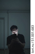 Solitary male silhouetted against dim interior, smartphone screen casting ghostly shadows while highlighting emotional isolation and digital disconnection. Стоковое AI-видео, аниматор Данил Руденко / Фотобанк Лори