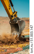 Heavy machinery digging on a construction site with dirt and debris flying around. Industrial concept for earthwork. Стоковое AI-изображение, AI-художник Анжелика Самсонова / Фотобанк Лори