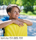 Close-up portrait of a beautiful short-haired Caucasian young woman with a yellow suitcase outdoors. The girl with a perfect smile dreamily leaned her head against a large luggage bag. Стоковое фото, фотограф Михаил Решетников / Фотобанк Лори