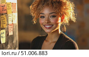 A woman with curly hair smiles while surrounded by sticky notes, actively brainstorming ideas in a bright, inviting workspace filled with creativity. Стоковое AI-видео, аниматор Данила Большаков / Фотобанк Лори