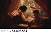 Cozy storytelling moments by candlelight create magical memories between parent and child in a cozy indoor setting. Стоковое AI-видео, аниматор Сергей Толмачёв / Фотобанк Лори