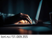 Person typing at laptop computer at night. Female uses keyboard, shakes buttons with fingers. Internet security, cyber attack. Trendy neon light. Creative dark color of orange, black, and teal blue. Стоковое AI-изображение, AI-художник Марина Демидюк / Фотобанк Лори