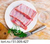 Raw meaty pork ribs slabs on plate with fresh greens. Стоковое фото, фотограф Яков Филимонов / Фотобанк Лори